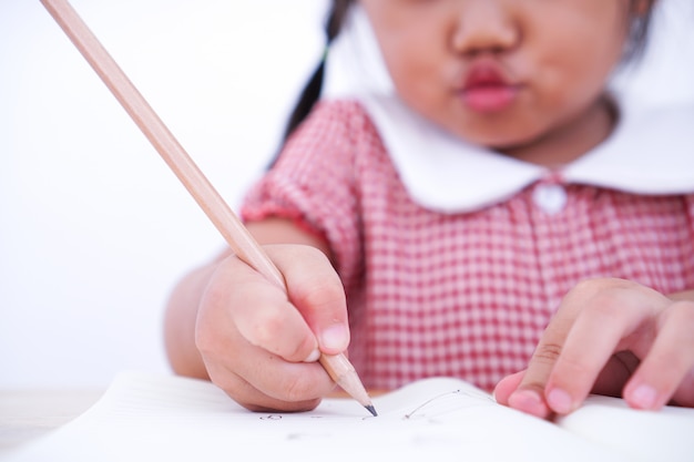 Foto chiuda sul piccolo bambino che impara scrivere sulla carta.