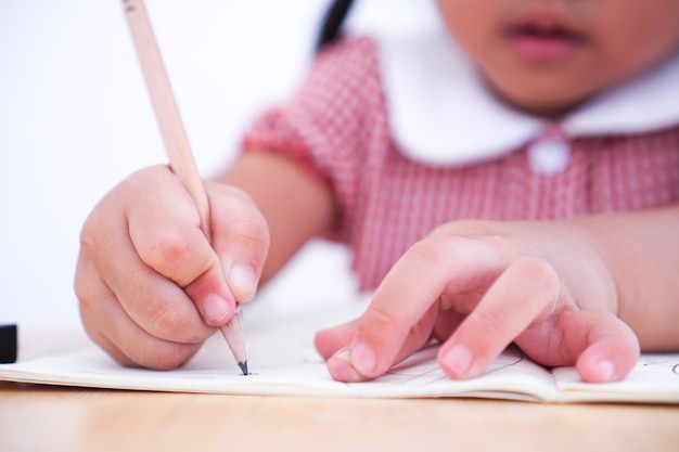 Foto chiuda sul piccolo bambino che impara scrivere sulla carta.