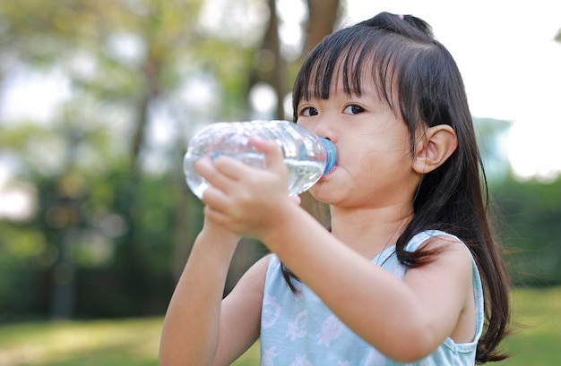 Close Up little girl drinking water from bottle in the park.