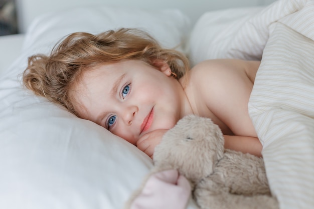 Close-up of a little girl sleeping and hugging her plush rabbit. Relaxation. Healthy sleep. Cozy.