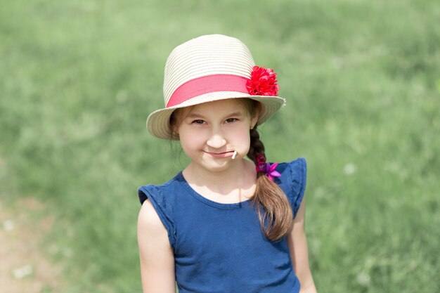 Close up. a little girl in a straw hat,standing on a green meadow