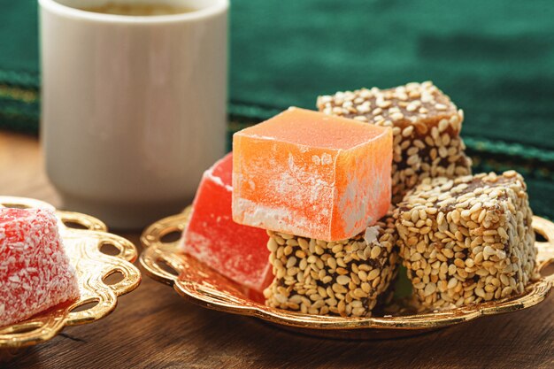 Close up of a little plate with turkish sweets and cup of espresso on wooden table