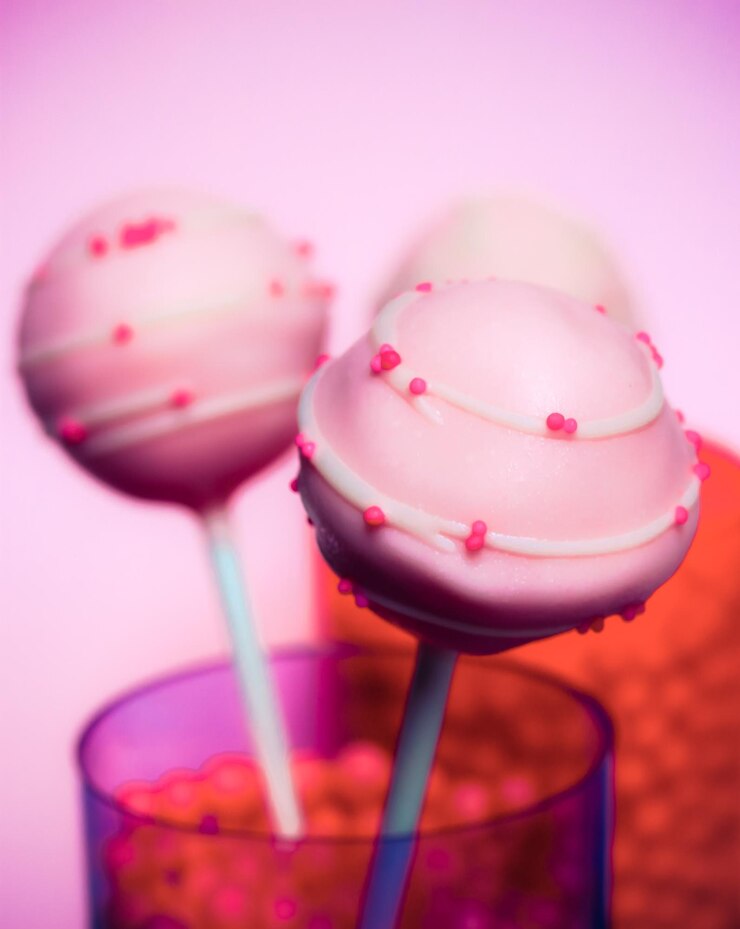 Photo close-up of lollipops in glass against pink background