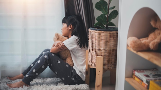 Close up lonely little girl hugging toy sitting at home alone\
upset unhappy child waiting for parents thinking about problems bad\
relationship in family psychological trauma