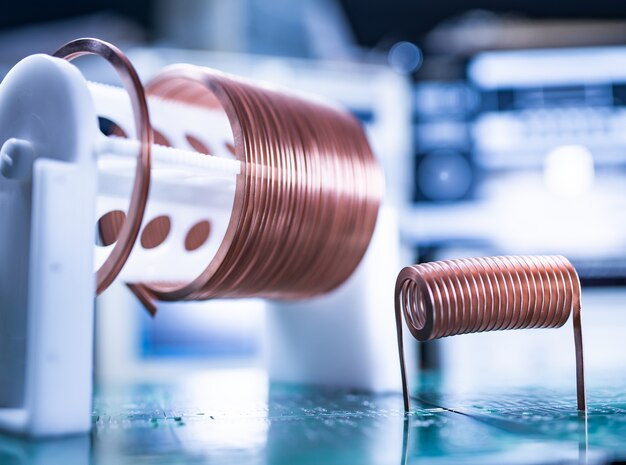 Close-up A lot of skeins of twisted copper wire are standing on a green microcircuit. Factory concept for the production of powerful oscillatory circuit and high-frequency components