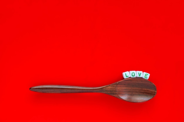 Close-up of love text by wooden spoon over red background