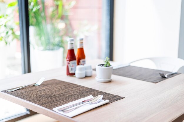 Close-up of luxurious spoon and fork, flower vaseson, sauce bottle the dining table decoration in hotel