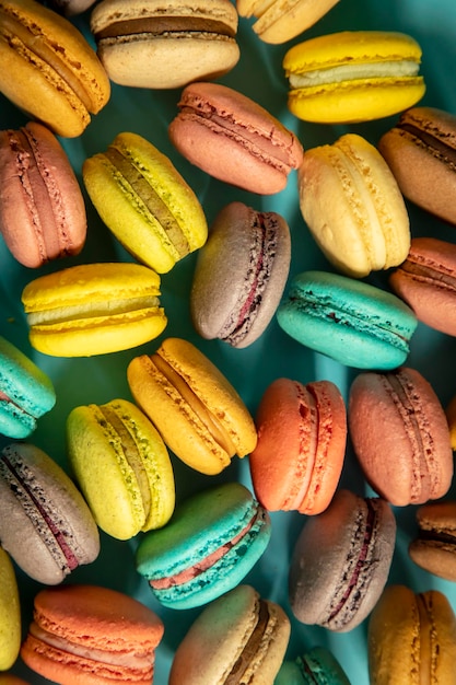 Close-up of macarons cakes of different colors in blue background. Culinary and cooking concept. Tasty colourful macaroons.