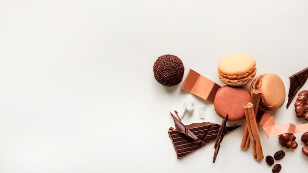 Close-up of macaroons and chocolate ball with ingredients on white background