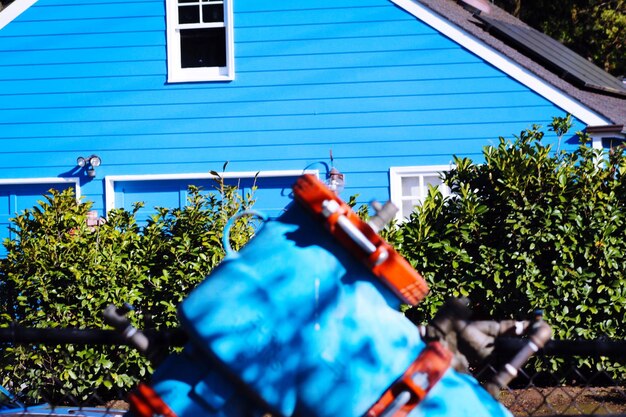 Photo close-up of machine part against blue house during sunny day