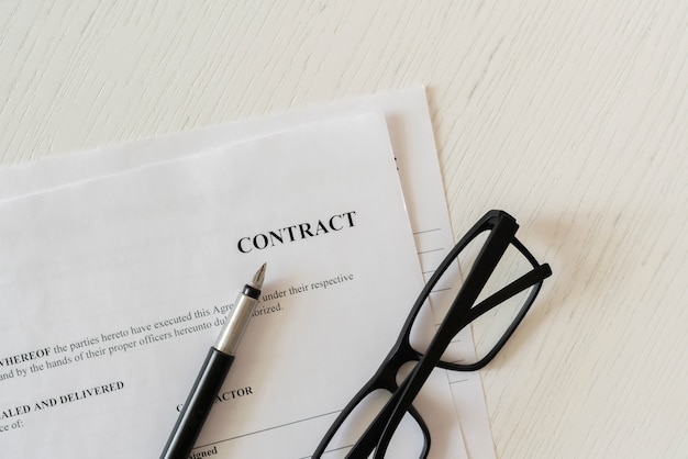 A close up macro view of a contract document with eye glasses and a pen