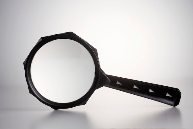 Photo close-up of magnifying glass against white background