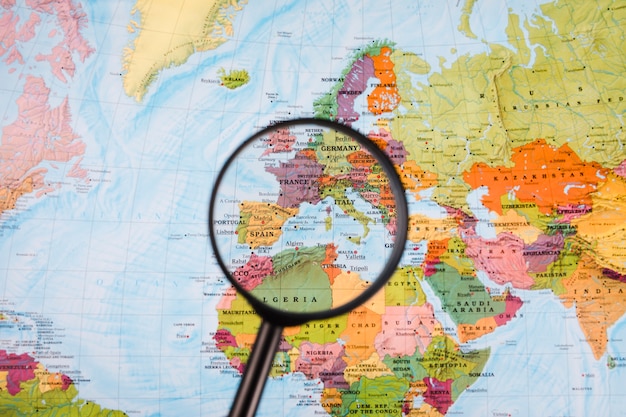 Close-up of magnifying glass in front of world map