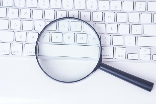 Photo close-up of magnifying glass on keyboard at table