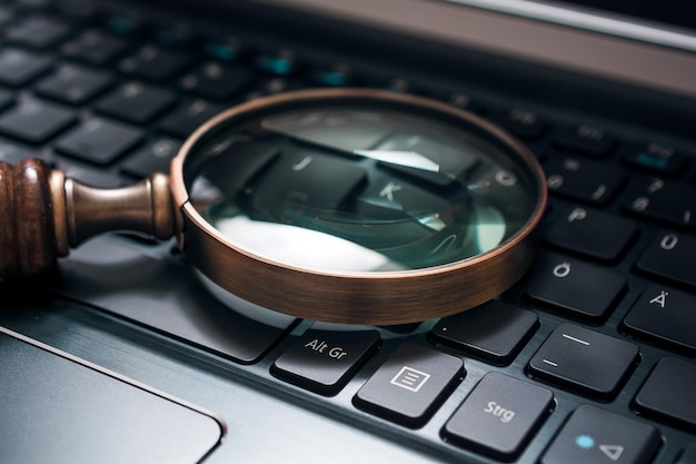 Photo close-up of magnifying glass laptop keyboard