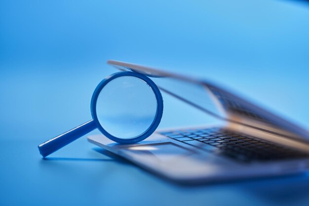 Photo close up of magnifying glass with small laptop