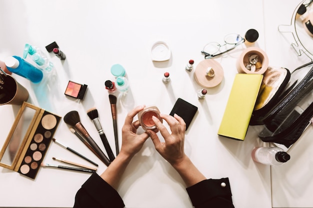 Close-up make-up artiest met een verscheidenheid aan cosmetische producten op bureau geïsoleerd