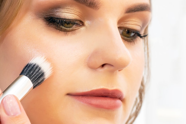 Close up on make-up artist applying various beauty products to model