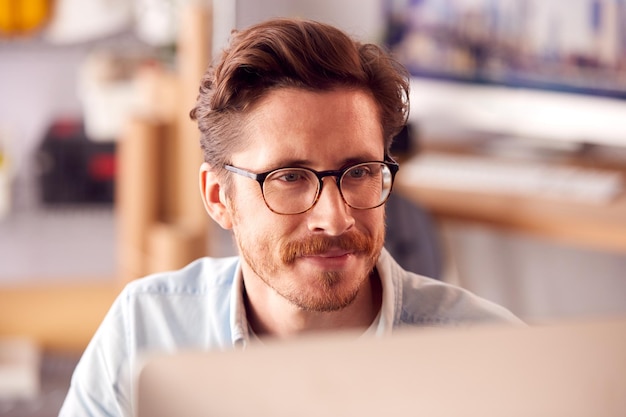 Close Up Of Male Architect In Office Working On Desktop Computer Viewed From Behind Screen