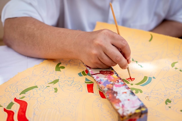 Foto primo piano le mani dell'artista maschile dipingono acquerelli su carta nell'area di lavoro