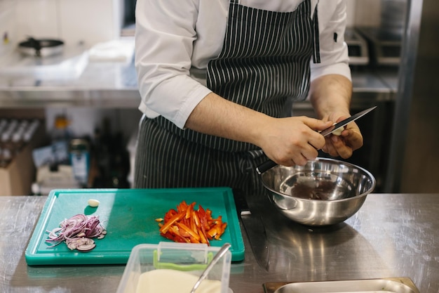 Close up male chef cuts vegetables in restaurant