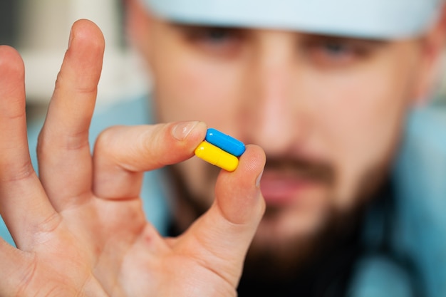 Close up of male doctor holding pill