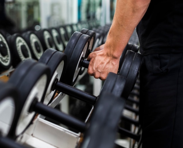 Photo close-up male at gym choosing weights