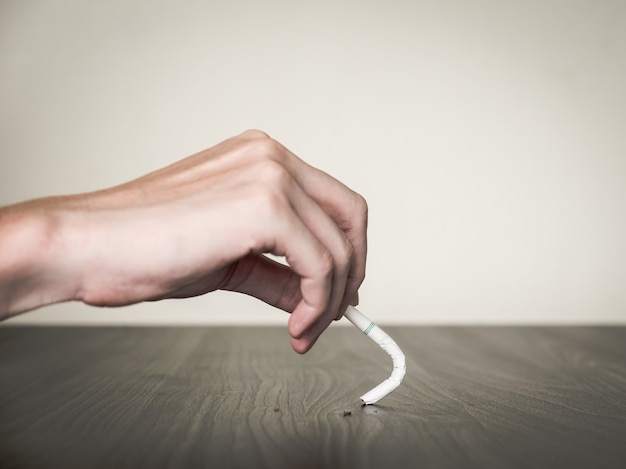 Close up of male hand destroying cigarette, stop smoking concept, soft focus