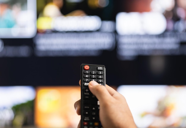 Close up male hand holding remote control pointing to change the programme television.