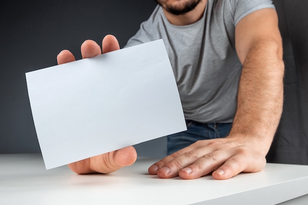 Close-up male hand holds a white card, mockup, layout, copy space.