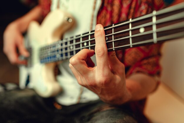 Foto close up di mano maschile che suona la chitarra elettrica al buio