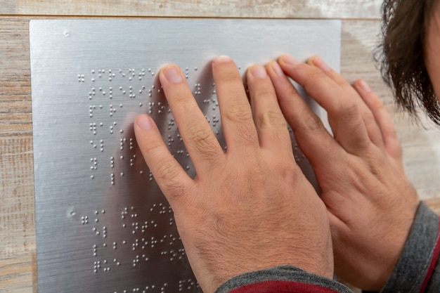 Close up of male hand reading braille text