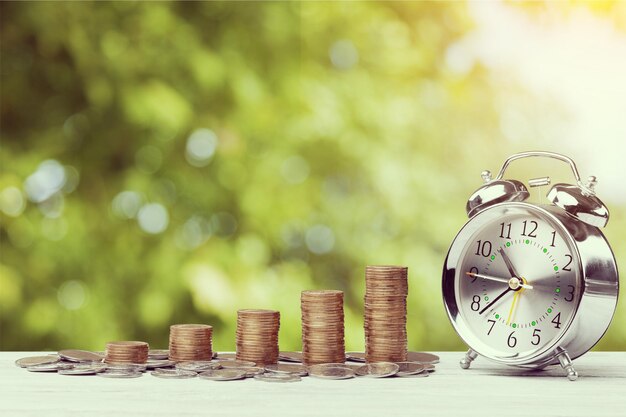 Close up of male hand stacking gold coins with green bokeh background ,