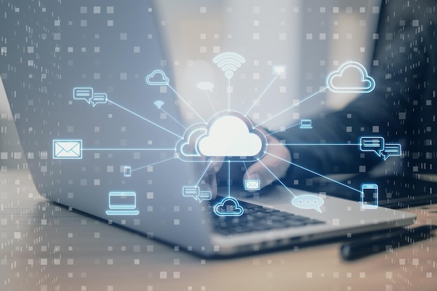 Close up of male hand using laptop with creative cloud computing hologram with various icons on blurry background Cyber data and media concept