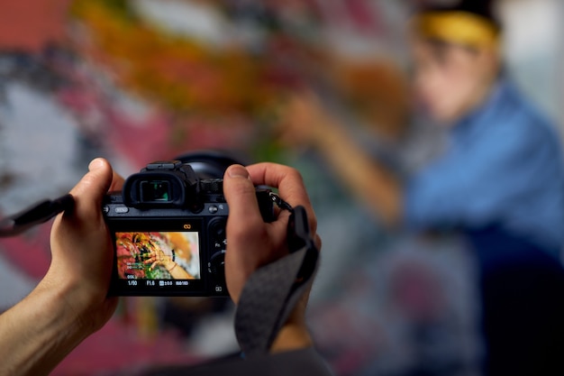 Close up of male hands holding professional digital camera on a blurred background female artist