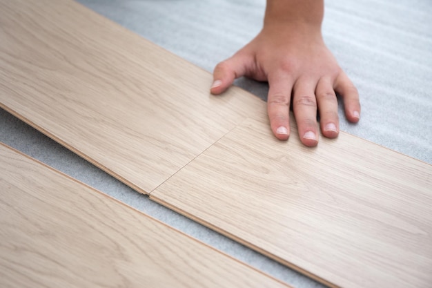 Foto primo piano di mani maschili che installano pavimenti in legno