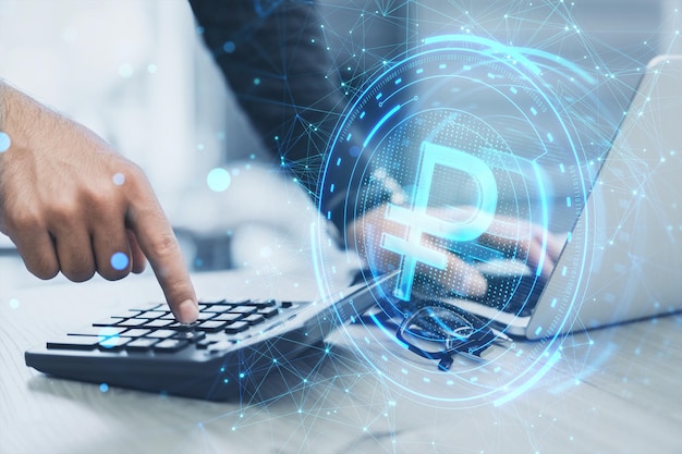 Photo close up of male hands using laptop and calculator with creative ruble hologram on blurry office desk background crypto online banking digital transformation and finance concept double exposure