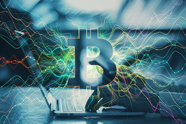 ぼやけた屋外の背景に光るビットコイン ホログラムとデスクトップ上のラップトップを使用して男性の手のクローズ アップ暗号通貨金融とブロックチェーンの概念二重露光