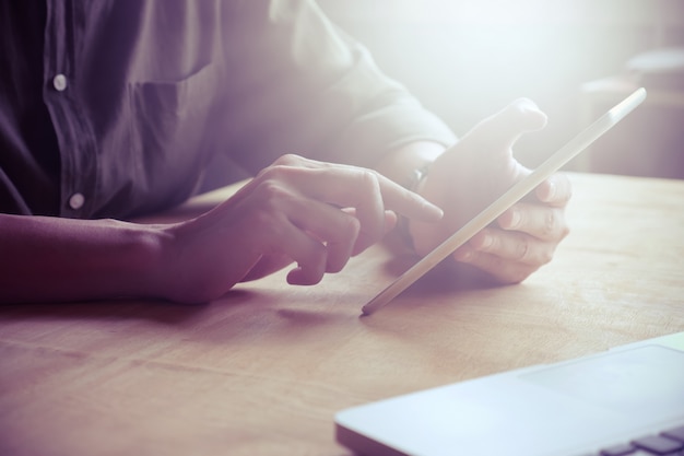 Close up of Male hands using tablet on the table, toned with sunlight