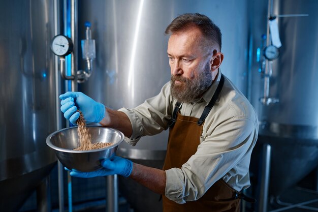 Close up of male hands wearing rubber gloves pouring wheat crops