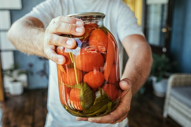 Close up of a male holding a jar with pickled vegetables