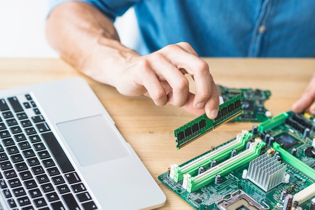 Photo close-up of male it engineer assembling ram on motherboard