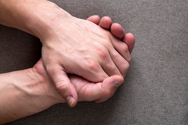 Close-up of male masculine young worker hands with rough skin and short fingernails resting