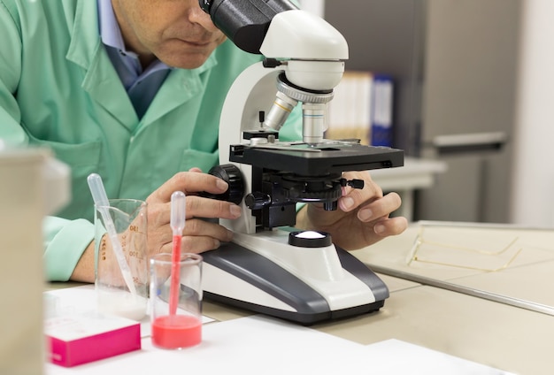 実験室で顕微鏡を使用して男性の科学研究者のクローズアップ