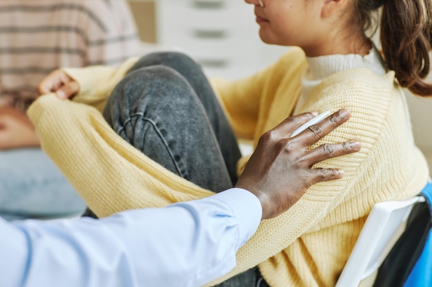 Photo close up of male therapist working with teenage girl in support group and supporting children