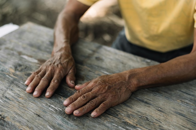 Close up of male wrinkled hands old man is wearing on the wood table