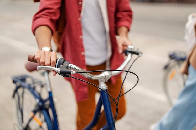 Крупный план рук мужчины 39, держащихся за ручки и толкающих велосипед на городской улице