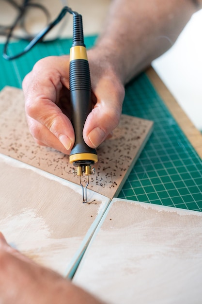 Close-up man aan het werk met de pyrograaf die het hout verbrandt en kunstwerken maakt in zijn kunststudio