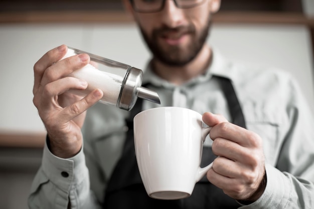 Close up a man adds sugar to a Cup of tea