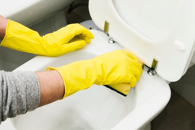 Close up man cleaning toilet with sponge